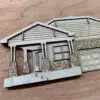 Wooden architectural model of a house with a stone foundation and gabled roof on a wooden surface
