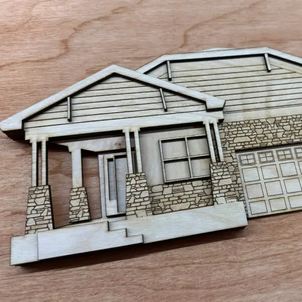 Wooden architectural model of a house with a stone foundation and gabled roof on a wooden surface