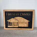 Wood-framed black chalkboard sign reading 'House of Doody' with a wooden house illustration plate beneath.