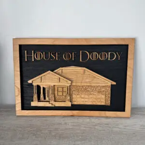 Wood-framed black chalkboard sign reading 'House of Doody' with a wooden house illustration plate beneath.