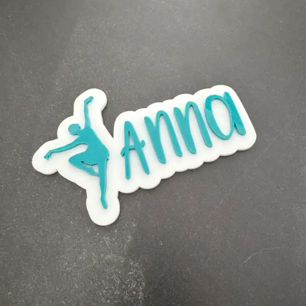 Teal acrylic name magnet reading Anna with a dancer silhouette on a white backing