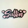 Black and pink acrylic name magnet reading Sutton with heart accents