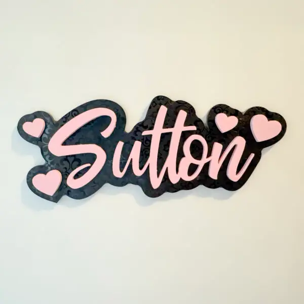 Black and pink acrylic name magnet reading Sutton with heart accents